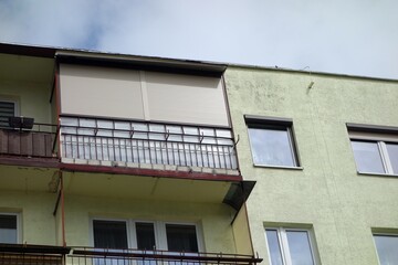 Barred window and balcony of a block of flats with anti-burglar shutters on the top floor