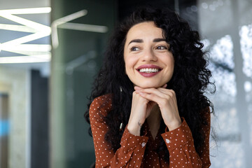 Beautiful and successful business woman inside office close up smiling and looking out the window,...