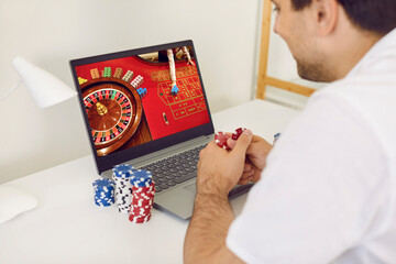 Gambling addict man plays and bets in online casino at home on his laptop computer. Online gambling...