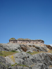 Fototapeta premium Marcahuasi chullpas, house made with stones on the top of a rocky mountain, archaeological remains in the mountains with a background of blue sky in South America