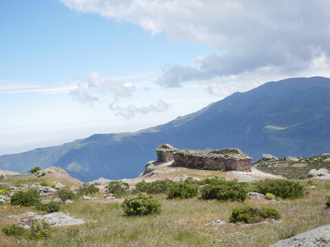 Marcahuasi chullpas, house made with stones next to the abyss, archaeological remains on the mountains with a background of blue sky with clouds