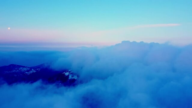 Low aerial view of morning flight, clouds and hills in the mountains in the blue hour before sunrise