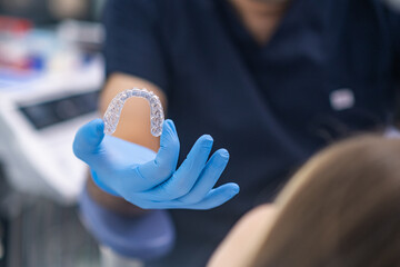 Bite correction in modern dentistry clinic closeup of orthodontist showing female patient transparent aligners designed for teeth alignment woman at dental appointment