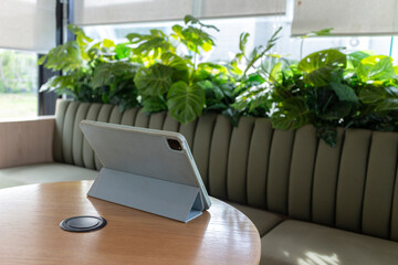 Tablets on wooden tables inside the café with chairs decorated with green leaves create a cool atmosphere.