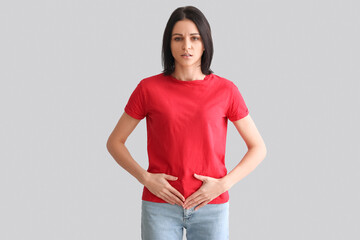 Young woman with menstrual cramps on grey background