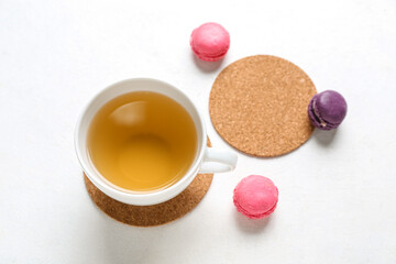 Obraz na płótnie Canvas Drink coasters with cup of tea and macaroons on white table