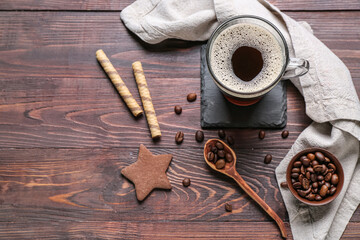 Drink coaster with cup of coffee, sweets and beans on wooden table