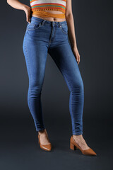 Young woman in skinny jeans on dark background