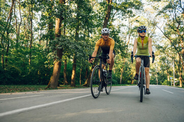 Couple riding bicycles outside of the city and wearing helmets and sunglasses