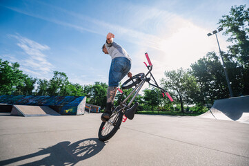 A professional mature bmx bike rider is practicing tricks in a skate park.