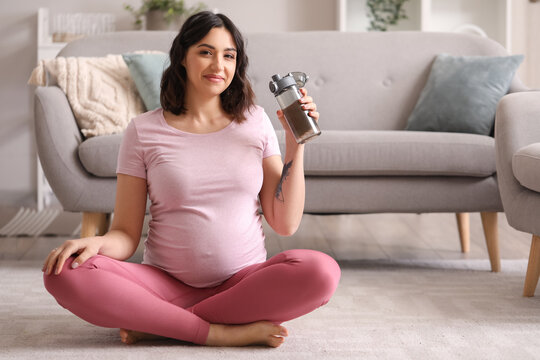 Sporty pregnant woman with bottle of water at home