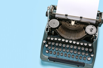Vintage typewriter with blank paper sheet on blue background