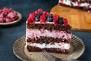 Chocolate cake with whipped cream and fresh berries. Piece of raspberry cake. Blueberry cake. Portion of cake. Summer dessert.
