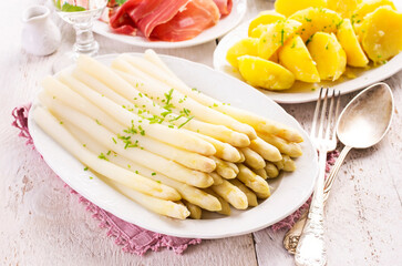Traditional German white asparagus with boiled potatoes  and serrano ham served as close-up on a...