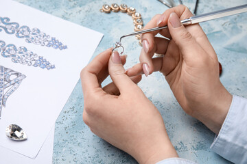 Female jeweler making adornment on grunge table, closeup