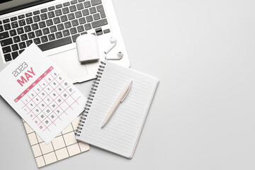 Composition with calendar, modern laptop, notebook and earphones on grey background