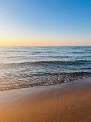 Fototapeta na wymiar Evening sea coast, sandy sea coastline, evening sea horizon, blue clear sky with some sunlight