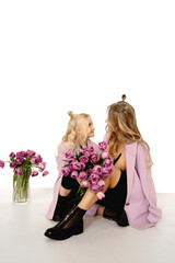 Family look : stylish mom with daughter - purple jackets , trendy black boots. Beautiful blonde models .
Festive bouquet of tulips in honor of Women's day on March 8 or Birthday. Fashion  concept .