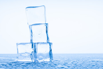 transparent Ice Cubes on a white table with reflection and water drops