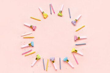 Frame made of whistles and candles for birthday party on pale pink background