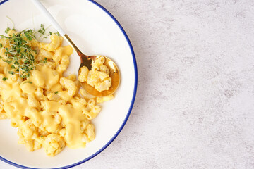 Bowl of tasty Italian pasta with Cheddar cheese on light background, closeup