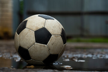 Fototapeta na wymiar Soccer ball in puddles on the street