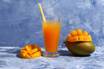 Glass of fresh mango smoothie on blue background