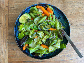Mixed vegetables with avocado and salad in ceramic bowl on wood table. Healthy meal for diabetics