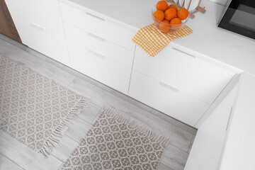 Stylish rugs on floor in light kitchen