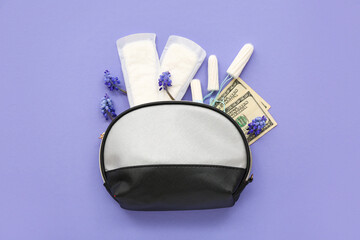 Fototapeta premium Lady's cosmetic bag with tampons, menstrual pads and money on violet background