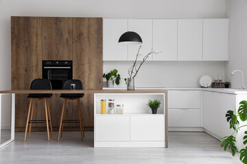 Interior of modern kitchen with island, built-in oven and white counters