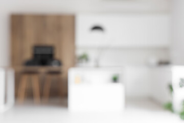 Interior of modern kitchen with island, built-in oven and white counters, blurred view