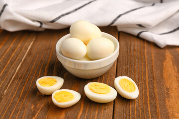 Bowl with boiled quail eggs on wooden background