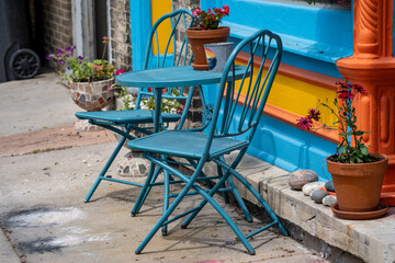 Cute, brightly painted table and chairs outside of a downtown cafe in a small town. Colors of blue, yellow and orange