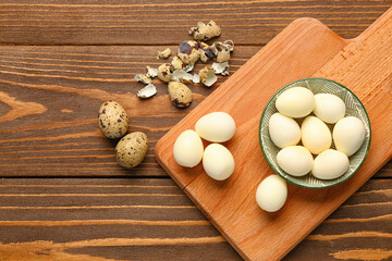 Fototapeta na wymiar Board with bowl of boiled quail eggs and shells on wooden background