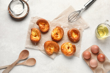 Tasty Yorkshire pudding and ingredients on light background