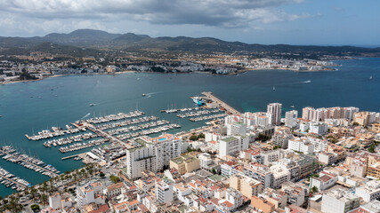 Naklejka premium Aerial drone photo of a beach in the town of Sant Antoni de Portmany on the island of Ibiza in the Balearic Islands Spain showing the boating harbour and harbour with hotels and apartments