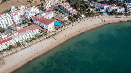 Straight down aerial drone photo in the beautiful town of Sant Antoni de Portmany in Ibiza Spain showing the beach known as Playa de San Antonio with people relaxing on the sandy beach in the summer