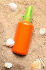 Bottle of sunscreen cream with seashells on sand