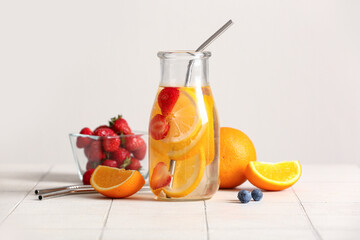 Bottle of infused water with orange slices on white tile table