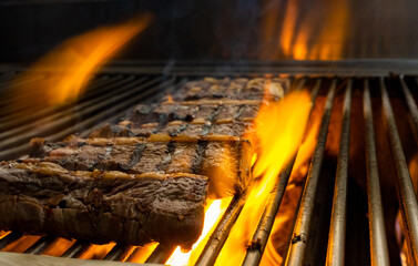 Picanha being roasted on char broiler with fire rising