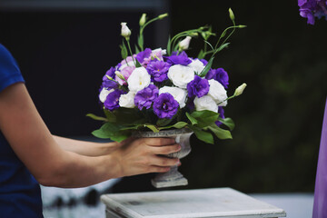 Wedding decorations with flowers. Florist girl gathered a bouquet of fresh purple flower.