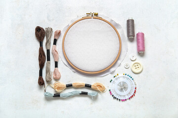 Wooden hoop with different embroidery supplies on grunge white background
