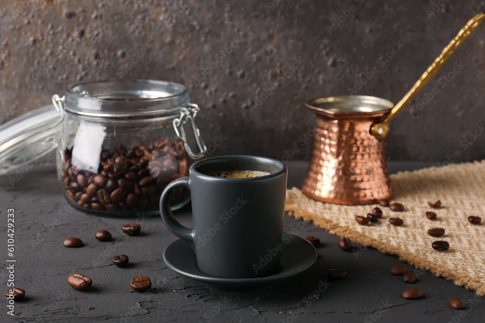 Wall mural Cup of delicious espresso, coffee beans and jezve on table