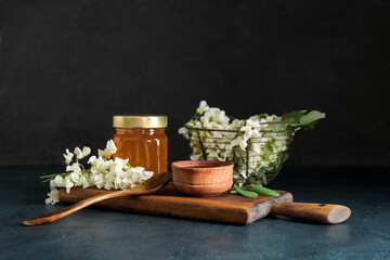 Jar and bowl of acacia honey on dark background
