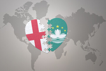 puzzle heart with the national flag of Macau and england on a world map background.Concept.