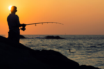 silhouette of a fisherman during sunset at the cliffs in sri lanka