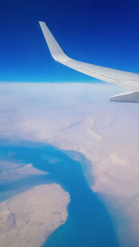 View from the window of plane on blue sky and earth with landscape of desert, sea and canals in Emirates. High quality photo