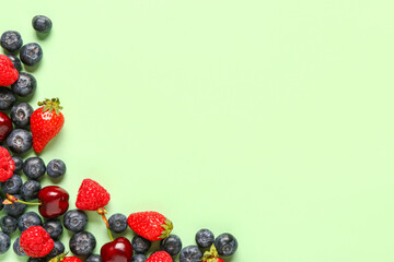 Different fresh berries on green background