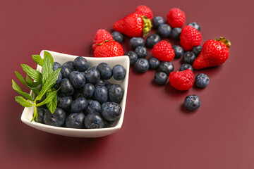 Bowl with different berries on red background